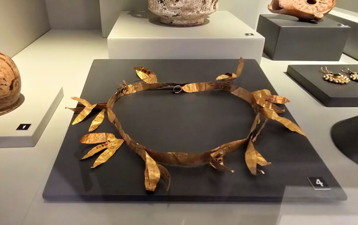 İznik Müzesi’nde sergilenen, Hellenistik dönemden kalma altın yapraklı taç örneği ve yan vitrindeki erken dönem takı buluntularının detaylı görünümü.